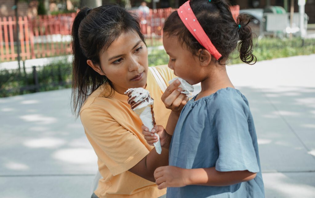 Responsible mother watching her daughter holding ice cream.